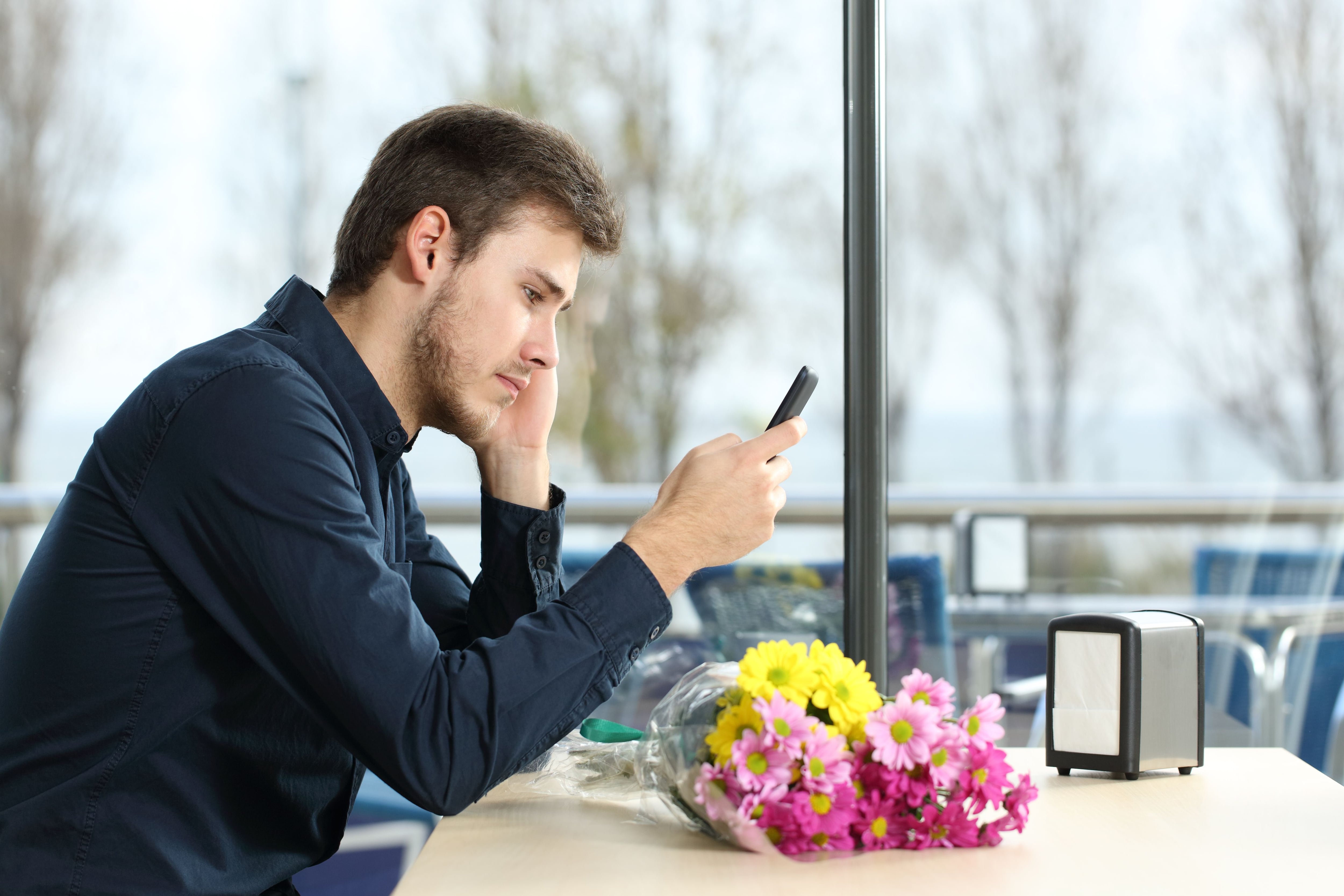 Un hombre triste observa su teléfono móvil (Shutterstock)
