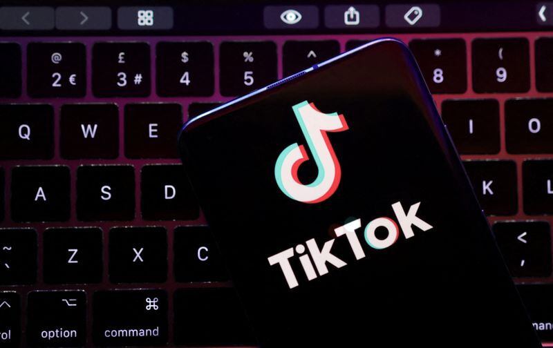 Ilustración del logo de TikTok en un teléfono móvil sobre una computadora