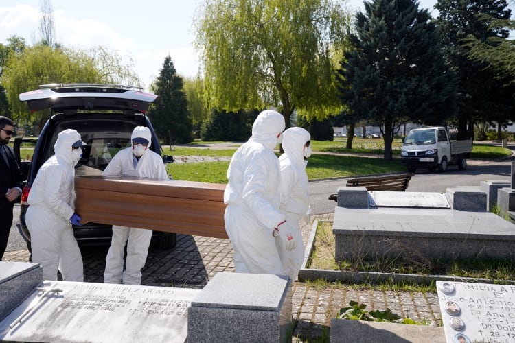 Trabajadores municipales con equipo de protección llevan el ataúd de una víctima del coronavirus en el cementerio de El Salvador en Vitoria, España (REUTERS/Vincent West)