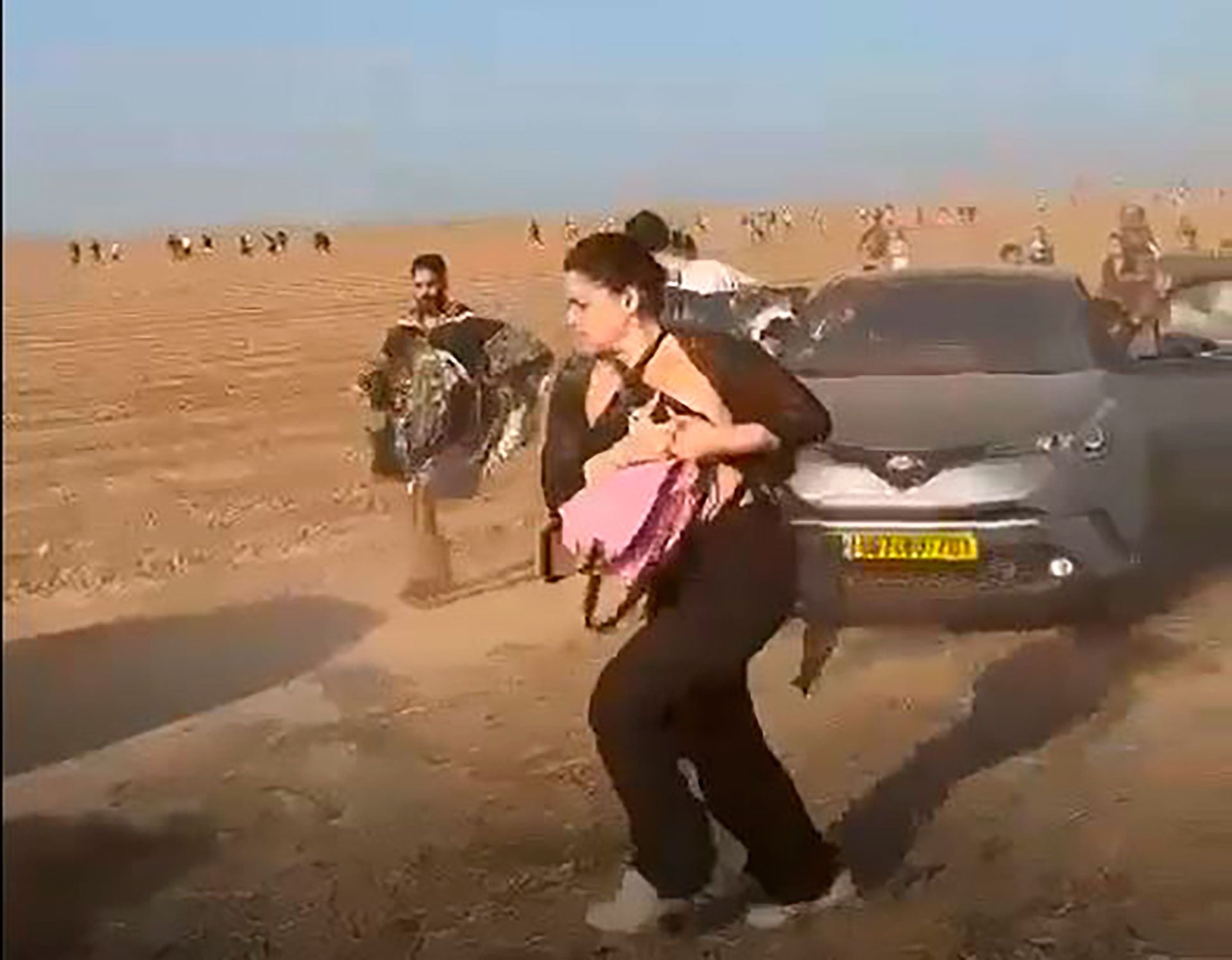 Gal, la hija de una argentina que estaba en la rave que atacó Hamas, en medio de la frenética huida con su mochila rosa. Detrás, de poncho, uno de los dos amigos que se salvaron con ella