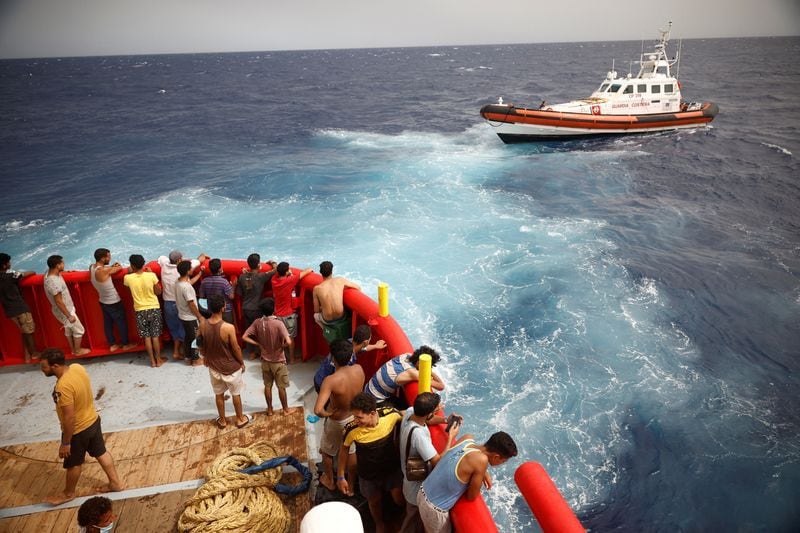 FOTO DE ARCHIVO: Migrantes a bordo del barco de rescate de la ONG Proactiva Open Arms Uno miran a un barco de la "Guardia Costiera" que se dirige a la isla de Lampedusa, en el mar Mediterráneo central, cerca de la isla de Lampedusa, Italia. 19 de agosto de 2022. REUTERS/Juan Medina