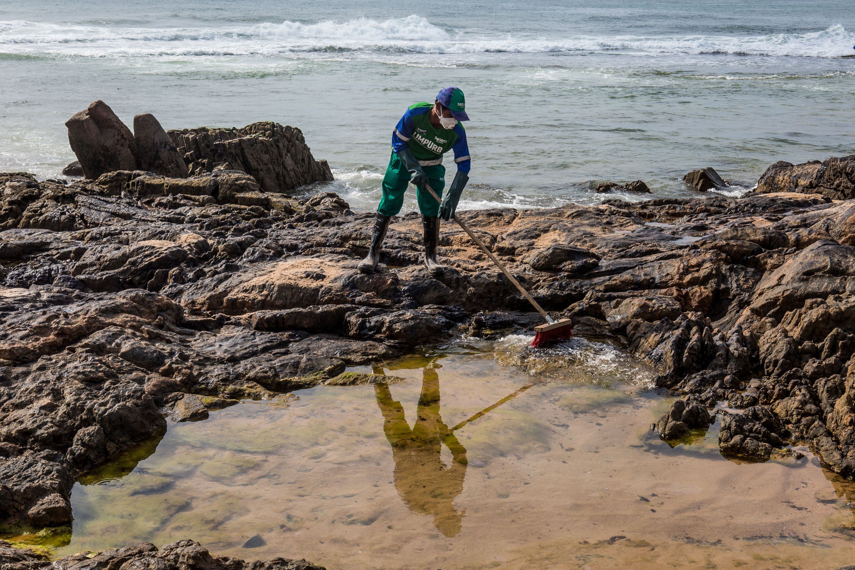 Un trabajador municipal extrae el crudo derramado en la playa de Pedra do Sal, en Salvador, estado de Bahía, Brasil, el 23 de octubre de 2019. -. (Photo by ANTONELLO VENERI / AFP)