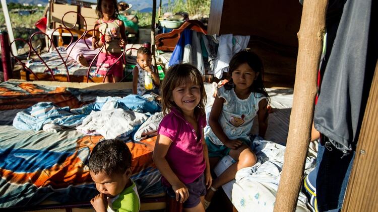 Niños que descansan con sus pertenencias en una vivienda improvisada después de cruzar el Río Táchira (EFE/archivo)