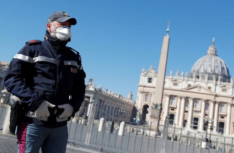 Un policía con mascarilla vigila una Plaza de San Pedro vacía desde Roma, Italia. 11 marzo 2020. REUTERS/Guglielmo Mangiapane