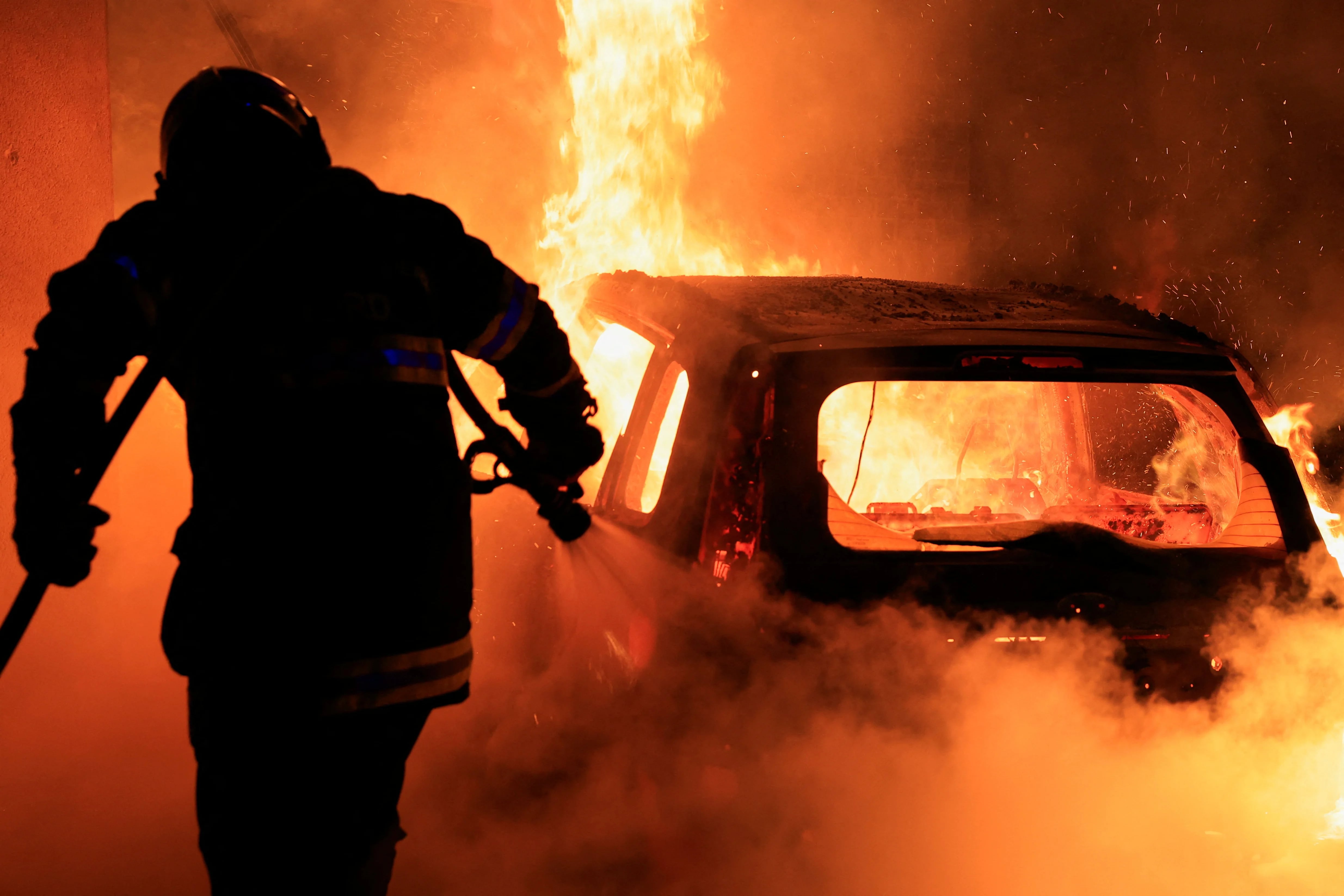 Quinta noche de disturbios en Francia. Un bombero trata de apagar el fuego que quema un vehículo (REUTERS/Pascal Rossignol)