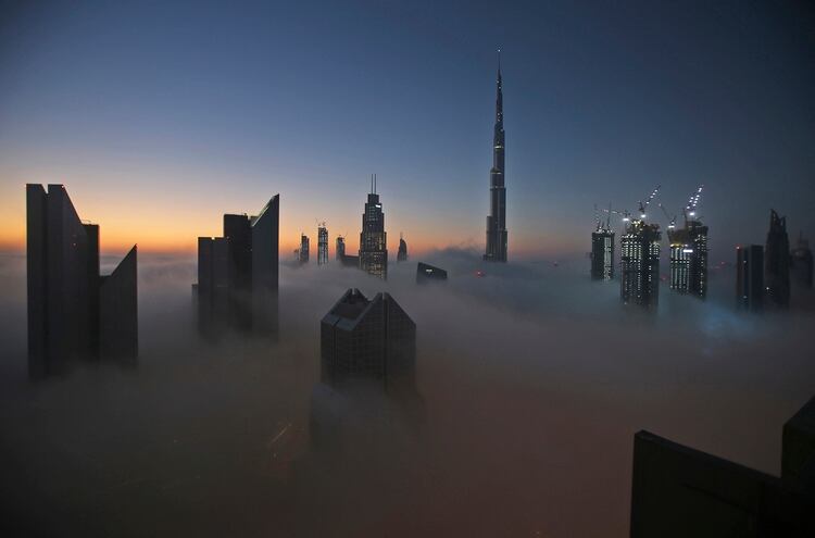 El sol sale sobre el horizonte de la ciudad con el Burj Khalifa, el edificio más alto del mundo como telón de fondo, visto desde un balcón en el piso 42 de un hotel en un día de niebla en Dubai, Emiratos Árabes (AP Photo/Kamran Jebreili)