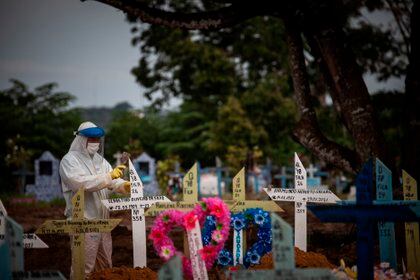 Un trabajador coloca cruces sobre la tumbas de personas fallecidas por covid-19, en el cementerio público Nossa Senhora Aparecida en Manaos, Amazonas (Brasil). EFE /RAPHAEL ALVES
