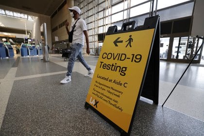 Un pasajero camina por detrás de un cartel que indica la ubicación de un centro de testeo de Covid-19 en el aeropuerto de California. Foto: REUTERS/Lucy Nicholson