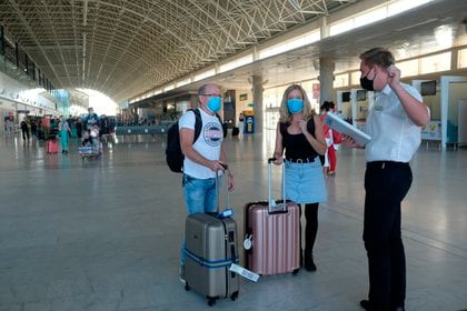 Un guía atiende a dos turistas recién llegados a Fuerteventur para disfrutar de sus vacaciones. EFE/ Carlos De Saá/Archivo

