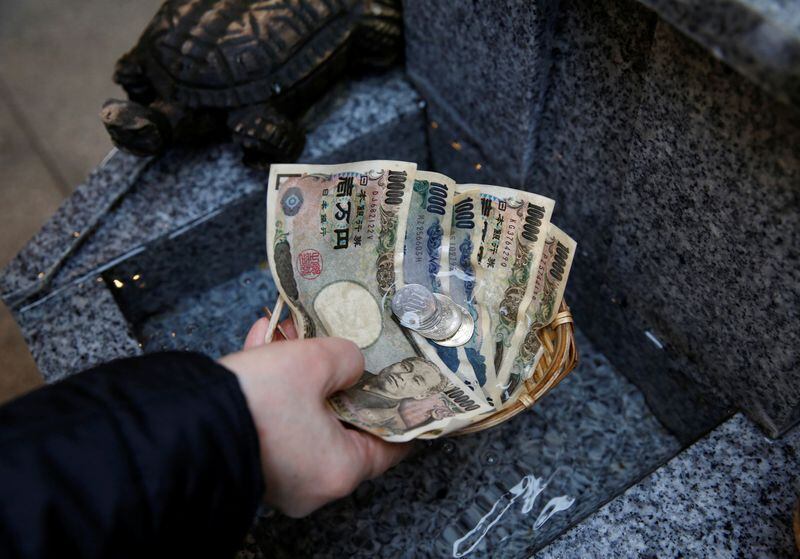 Un visitante lava billetes y monedas de yenes para rezar por la prosperidad en el santuario de Koami en el distrito de negocios Nihonbashi de Tokio, Japón, 13 noviembre 2017.REUTERS/Toru Hanai