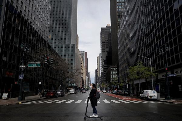 A woman wearing a protective face mask rides a scooter across a nearly empty 3rd Avenue in midtown Manhattan during the outbreak of the coronavirus disease (COVID-19) in New York City, New York, U.S., April 21, 2020. REUTERS/Mike Segar