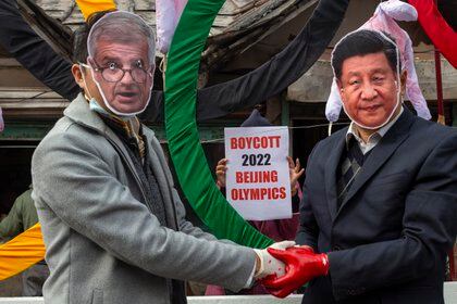 Activistas con máscaras del presidente del COI, Thomas Bach, a la izquierda, y del presidente chino, Xi Jinping, posan frente a los Anillos Olímpicos durante una protesta callejera contra la celebración de los Juegos Olímpicos de Invierno de Beijing 2022, en Dharmsala, India. (AP Photo/Ashwini Bhatia, archivo)