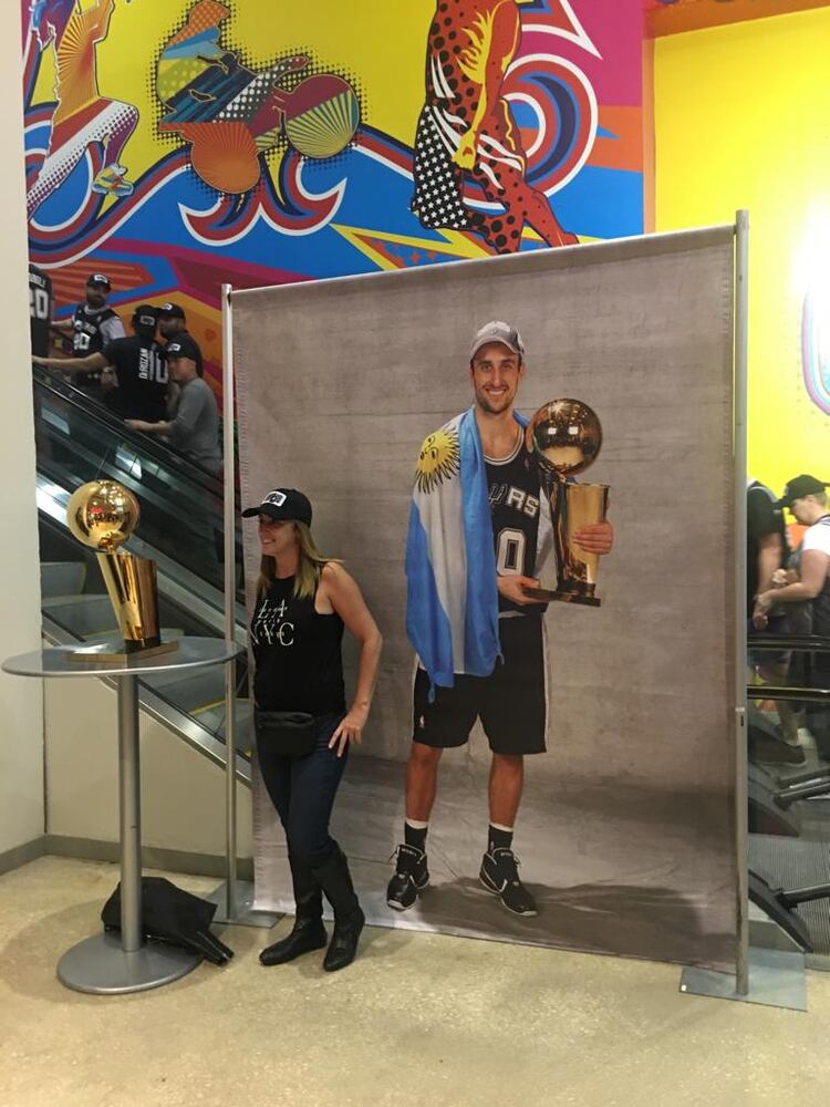 Los fanáticos de “Manu” Ginóbili se toman fotografías junto al trofeo de campeón de la NBA y el afiche del bahiense detrás