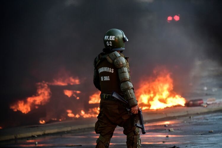 Un carabinero camina cerca del fuego en Viña del Mar (MARTIN BERNETTI / AFP)