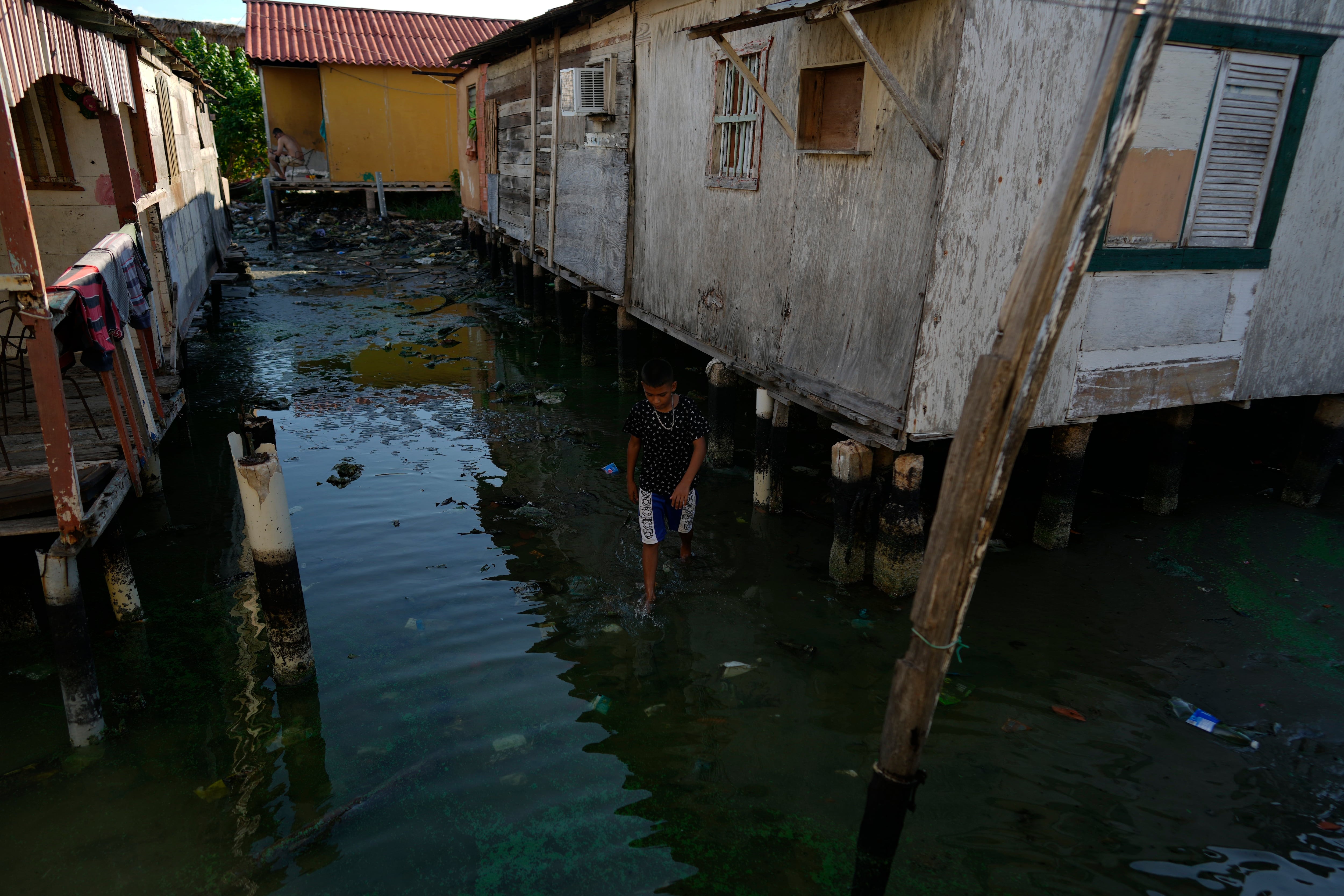 Un niño camina por la orilla entre dos casas elevadas (AP Foto/Ariana Cubillos)