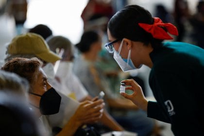 A health worker shows a vial of the Sputnik V coronavirus disease (COVID-19) vaccine to a person during a mass vaccination in Mexico City, Mexico February 24, 2021. REUTERS/Carlos Jasso