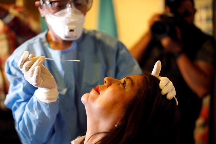 Una médica en Guatemala toma con un hisopo una muestra de saliva de una mujer que provino de Europa - REUTERS/Luis Echeverria