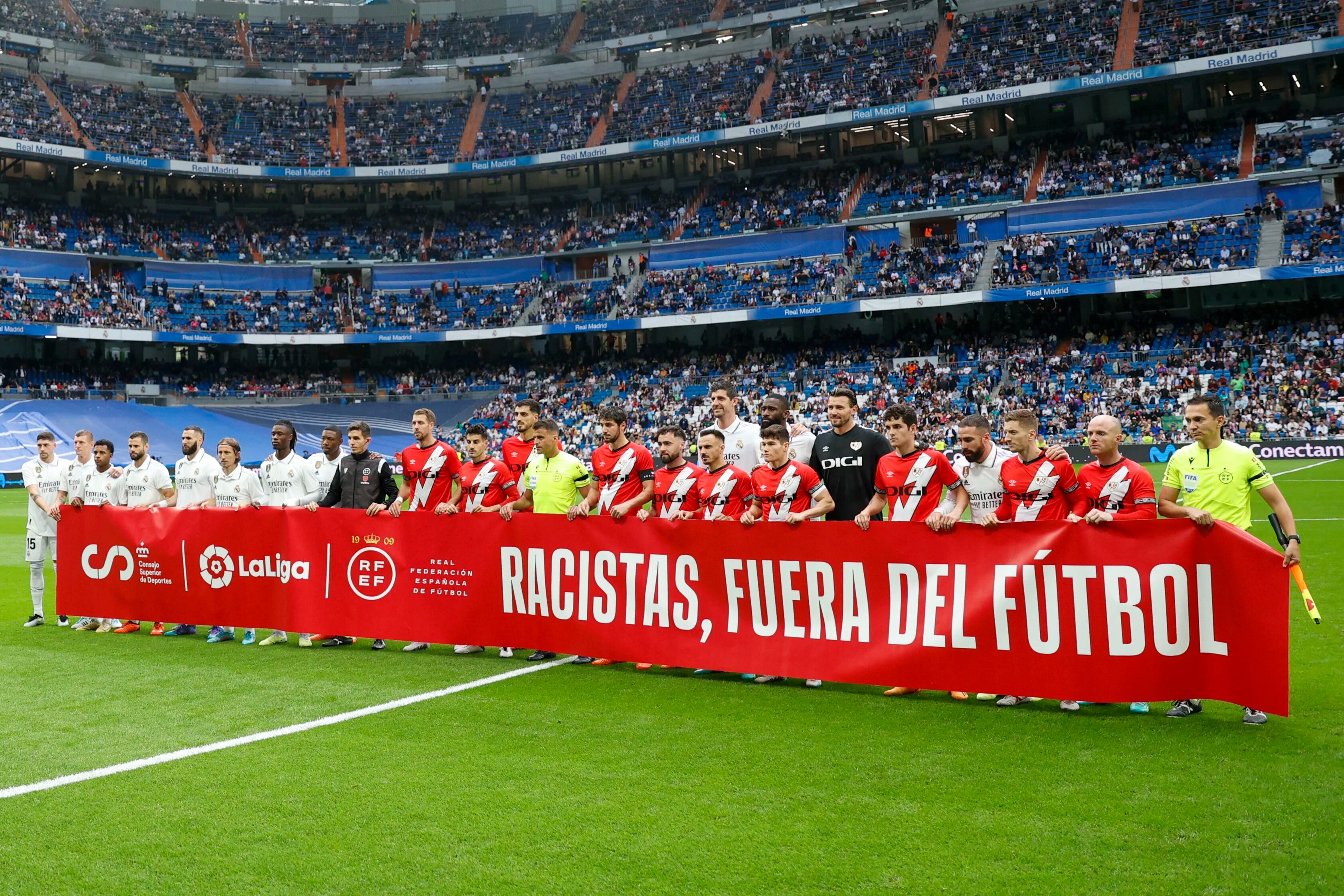 Jugadores del Real Madrid y el Rayo Vallecano con una pancarta de apoyo a Vinicius. (EFE/Rodrigo Jiménez)
