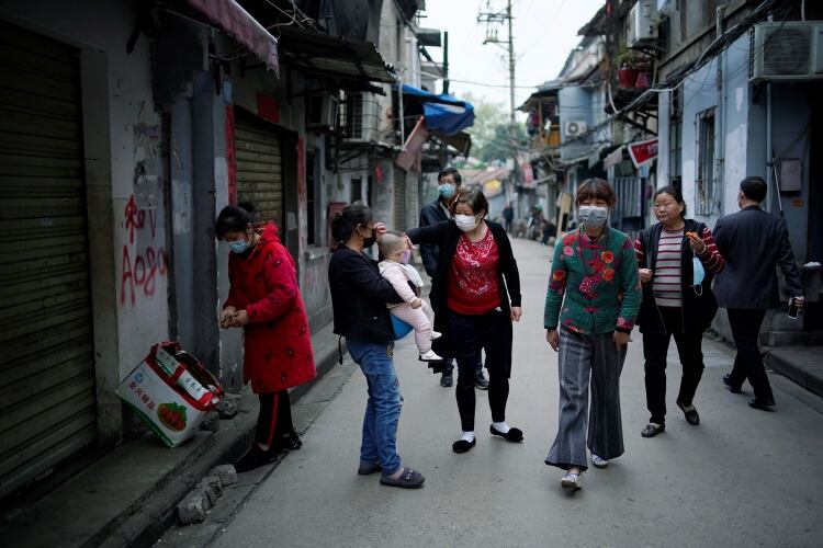 Algunos residentes de Wuhan caminan pos sus calles con máscaras, a medida que en los últimos días se fueron relajando las medidas de aislamiento.