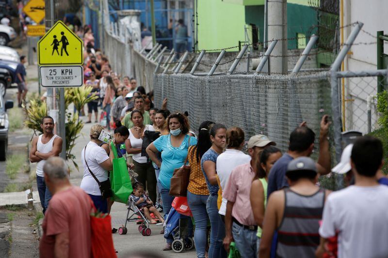 Personas esperan en un punto de distribución de frutas y verduras donadas por productores nacionales que no pueden exportar debido a la pandemia del coronavirus, en San José, Costa Rica el 13 de abril de 2020 (REUTERS/Juan Carlos Ulate)