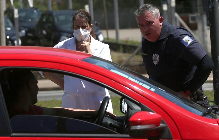 Una trabajadora de la salud y un oficial de policía hablan con un conductor en una barrera sanitaria en San Pablo, Brasil (REUTRES/Rahel Patrasso)