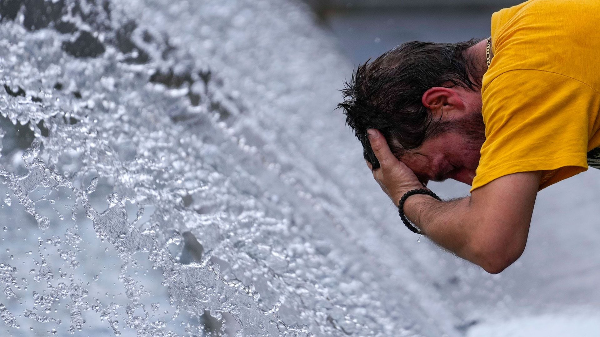 Un hombre se refresca en una fuente  (AP Foto/Darko Vojinovic)