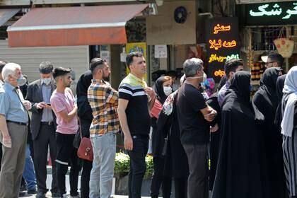 Ciudadanos iraníes sin observar el distanciamiento social hacen cola frente a una oficina de cambio en la capital Teherán el 9 de mayo de 2020 (Foto de ATTA KENARE / AFP)