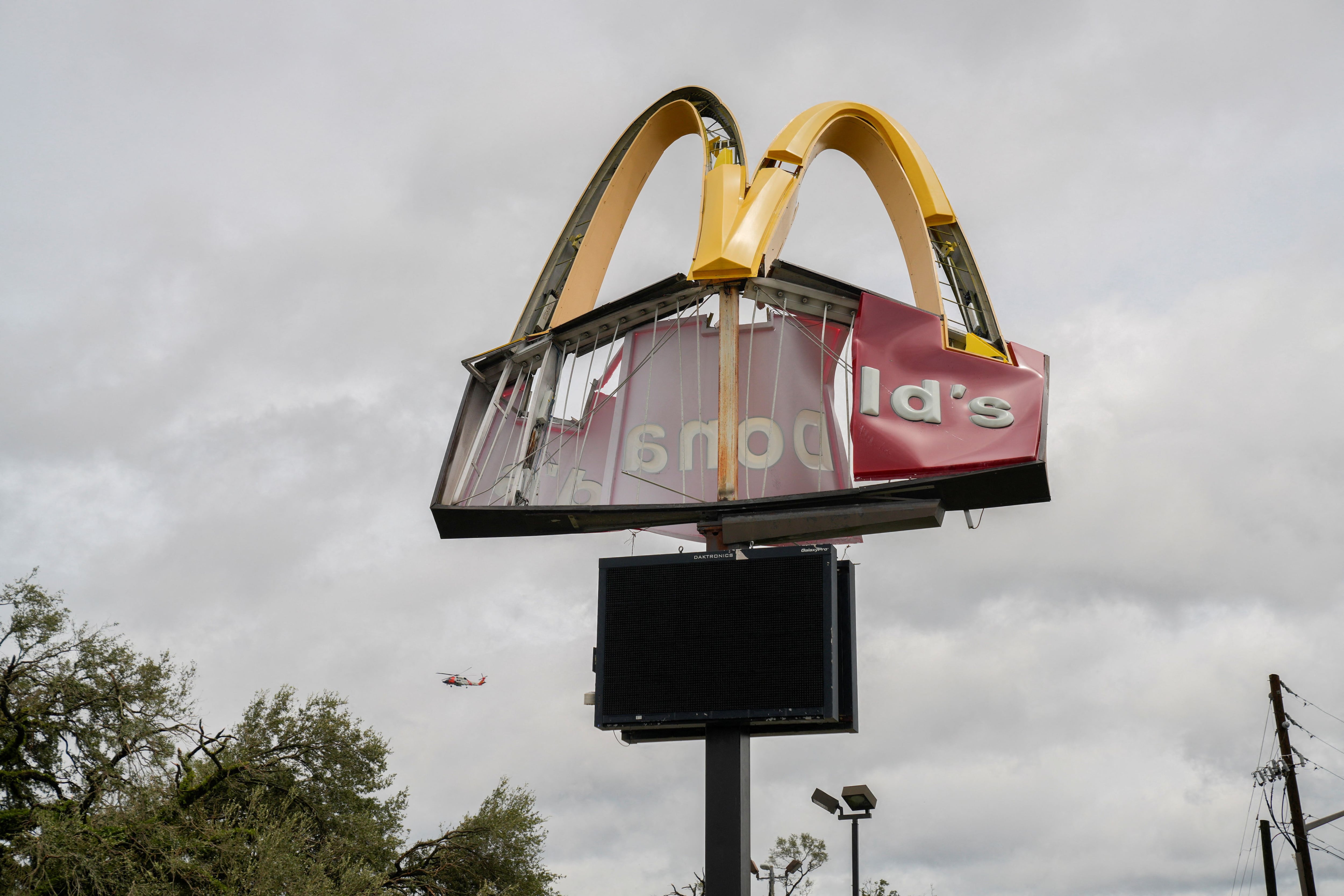 A search and rescue helicopter flies behind a damaged McDonald's sign after Hurricane Italia made landfall in Perry, Florida, U.S., on August 30, 2023.  REUTERS/Cheney Orr