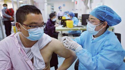 Un hombre con mascarilla para combatir los contagios de coronavirus recibe una dosis de la vacuna de Sinovac contra el COVID-19 en un centro de salud en Hangzhou, en la provincia oriental china de Zhejiang, el lunes 15 de marzo de 2021. (Chinatopix Via AP)