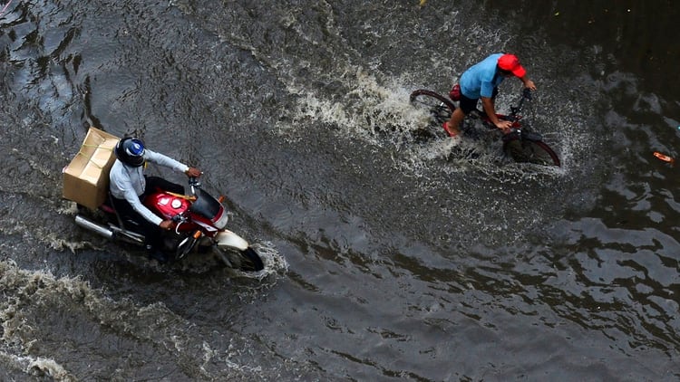 Ciclistas y motociclistas manejan sobre el agua en Allahabad, India (Photo by SANJAY KANOJIA / AFP)