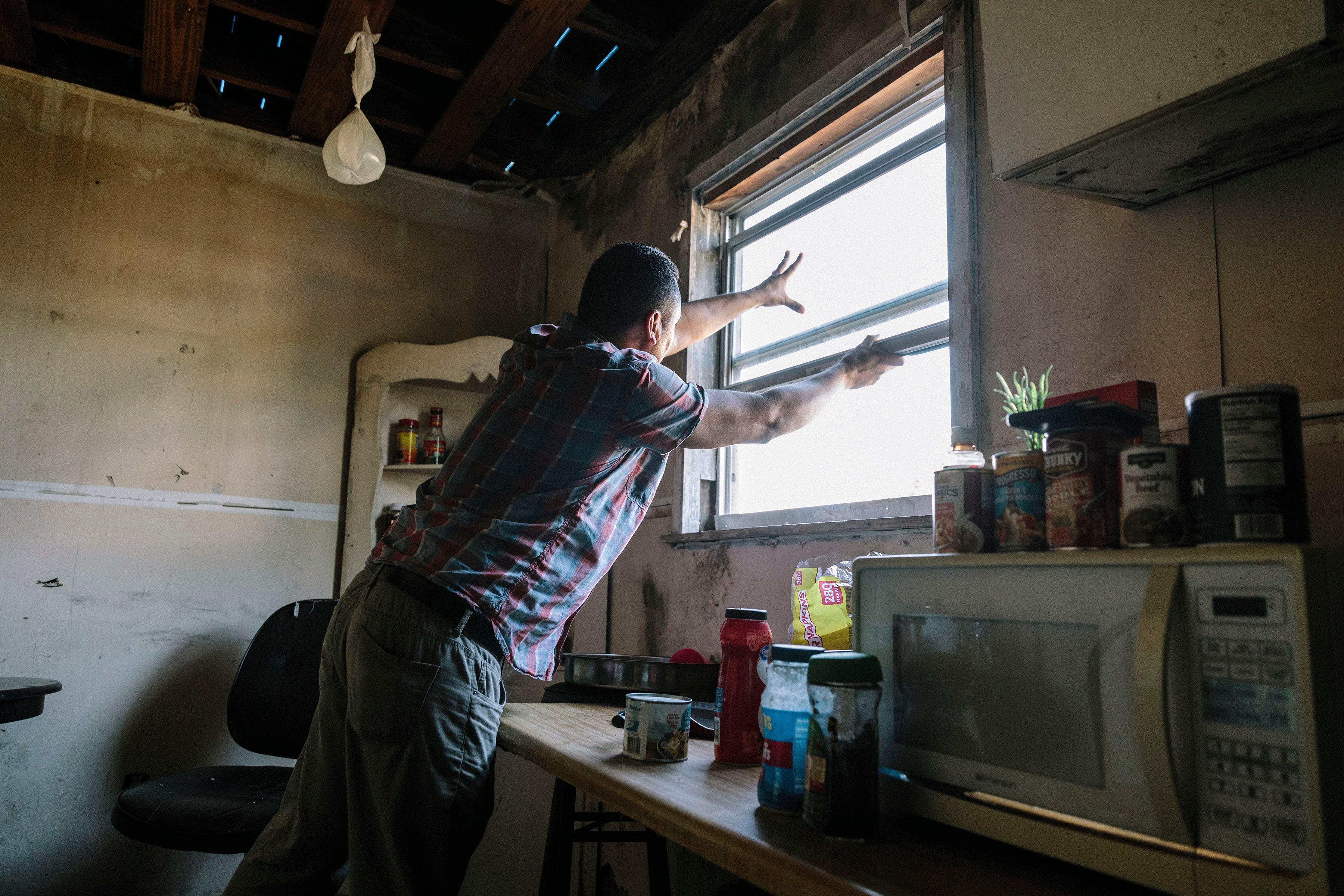 Will, un inmigrante indocumentado de Honduras, levanta una ventana en una casa dañada que él y otros cuatro están alquilando mientras reparan otras casas azotadas por el huracán Michael (William Widmer/The New York Times)