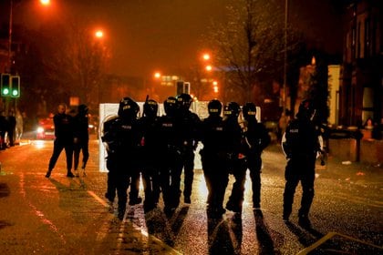 Agentes de policía de pie detrás de escudos caminan por Springfield Road durante las protestas en Belfast, Irlanda del Norte, el 7 de abril de 2021 (REUTERS/Jason Cairnduff)