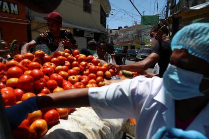 La gente recoge productos descartados de una camioneta debido a que menos gente está comprando en el mercado, en Santo Domingo, República Dominicana, el 15 de abril de 2020. (REUTERS/Ricardo Rojas)