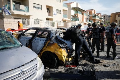 Agentes de la policía israelí inspeccionan un coche dañado en un lugar donde cayó un cohete disparado desde Gaza, mientras continúa la violencia transfronteriza israelí-palestina, en Ashkelon, sur de Israel, 16 de mayo de 2021. REUTERS/Amir Cohen
