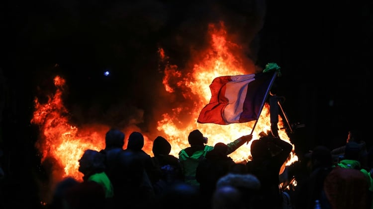 Una bandera de Francia flamea en medio de los incendios (Photo by Geoffroy VAN DER HASSELT / AFP)