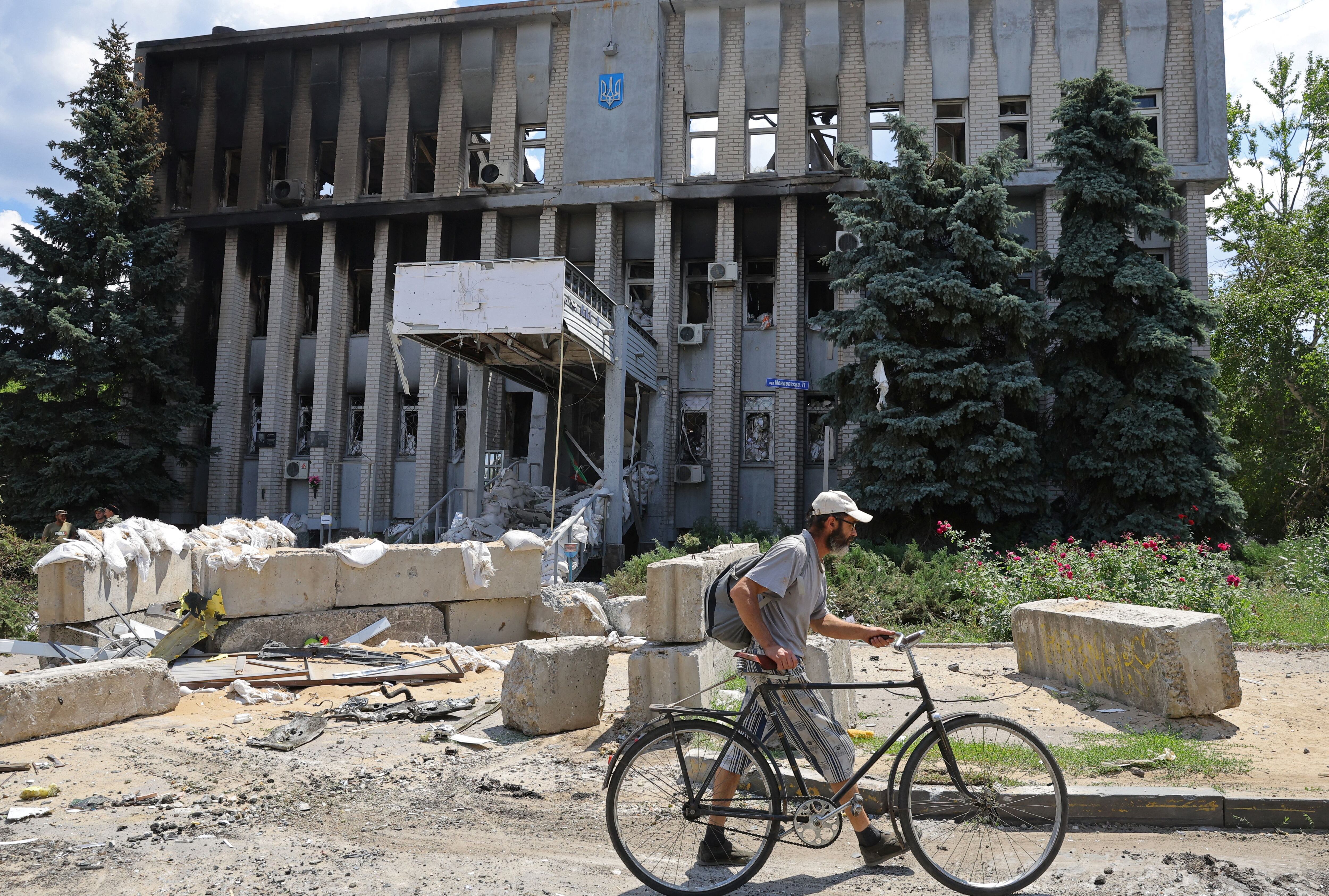 A local resident walks past a destroyed building of the police department in Lysychansk