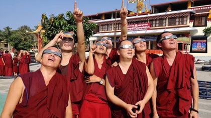 Monjes con gafas de filtro solar observan un eclipse solar de "anillo de fuego" en el monasterio de Gaden en una colonia tibetana en Teginkoppa, a 50 km al sur de Dharwad en el estado meridional de Karnataka, en la India, el 26 de diciembre de 2019. (Foto de Rakesh Nagar / AFP)