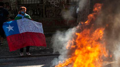 Una mujer muestra una bandera frente a una barricada (Martin BERNETTI / AFP)