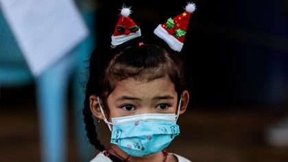 Una niña con máscara espera ver a Santa Claus, una imagen que se repite en el mundo (AFP)