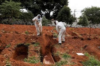 Sepultureros con trajes protectores entierran el ataúd de una persona que murió de la enfermedad por coronavirus (COVID-19), en el cementerio de Vila Formosa, el más grande de Brasil, en Sao Paulo, Brasil, 13 de mayo de 2020. REUTERS / Amanda Perobelli