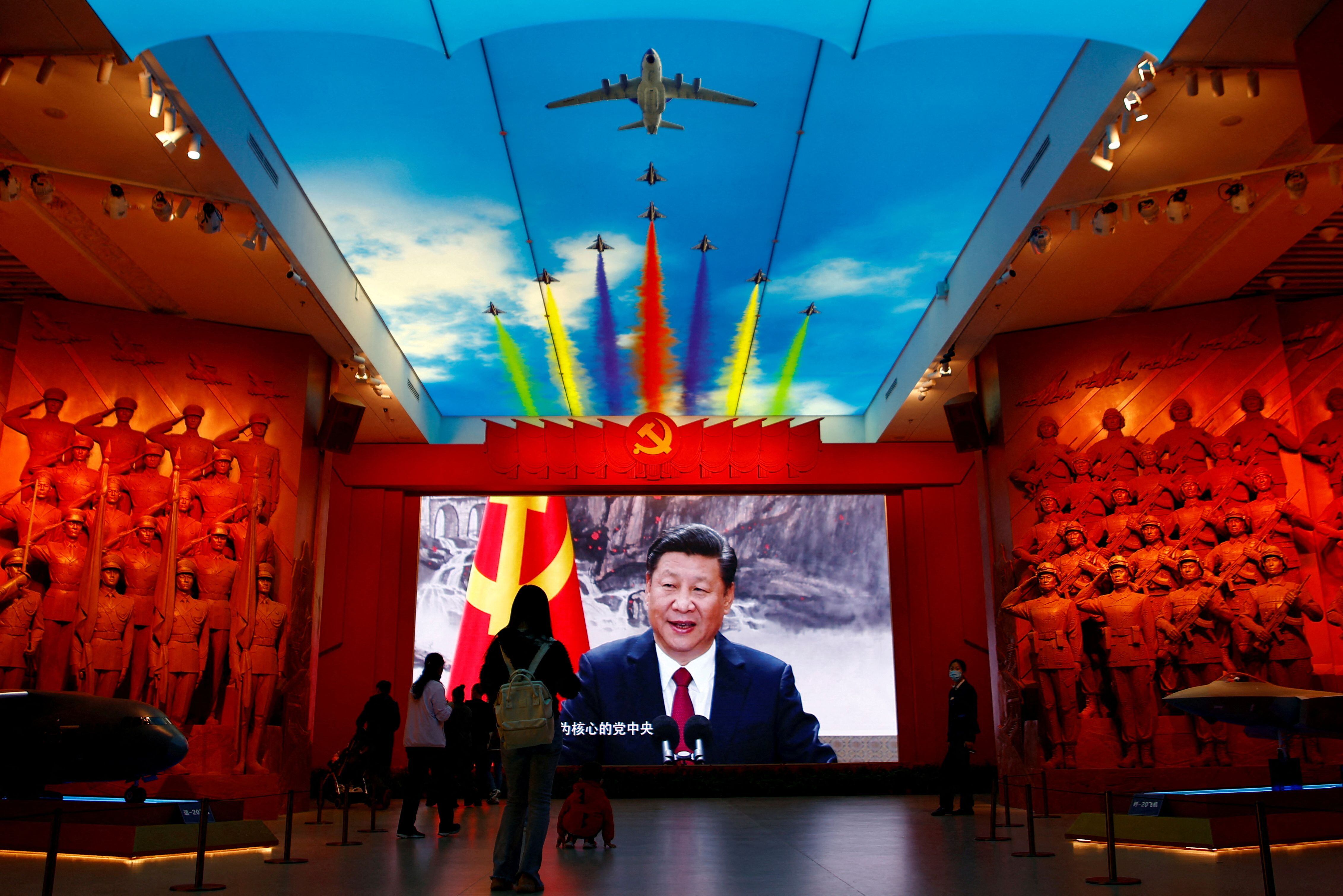 FOTO DE ARCHIVO: Los visitantes se paran frente a una pantalla gigante que muestra al presidente chino, Xi Jinping, junto a una bandera del Partido Comunista de China, en el Museo Militar de la Revolución Popular China en Beijing, China, el 8 de octubre de 2022. Para coincidir con el Informe especial de EE. UU. -CHINA/TECH-TAIWÁN REUTERS/Florence Lo/Foto de archivo