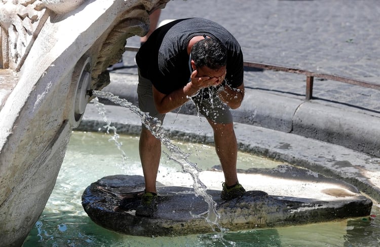 Un hombre se refresca en una fuente romana. (Riccardo Antimiani/ANSA via AP)
