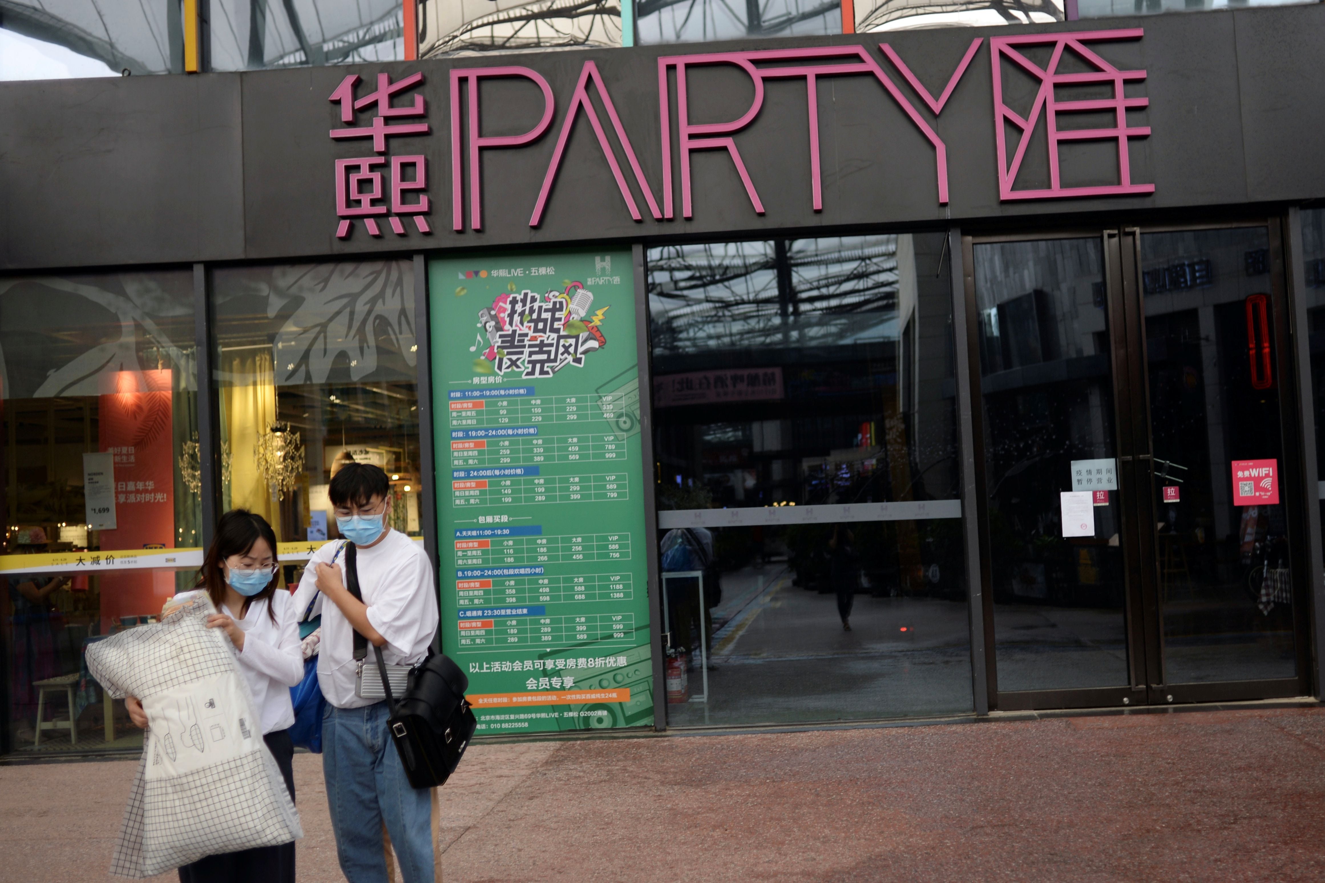 Personas con caminan frente a un karaoke en Beijing, China, el 18 de junio de 2020. REUTERS / Tingshu Wang
