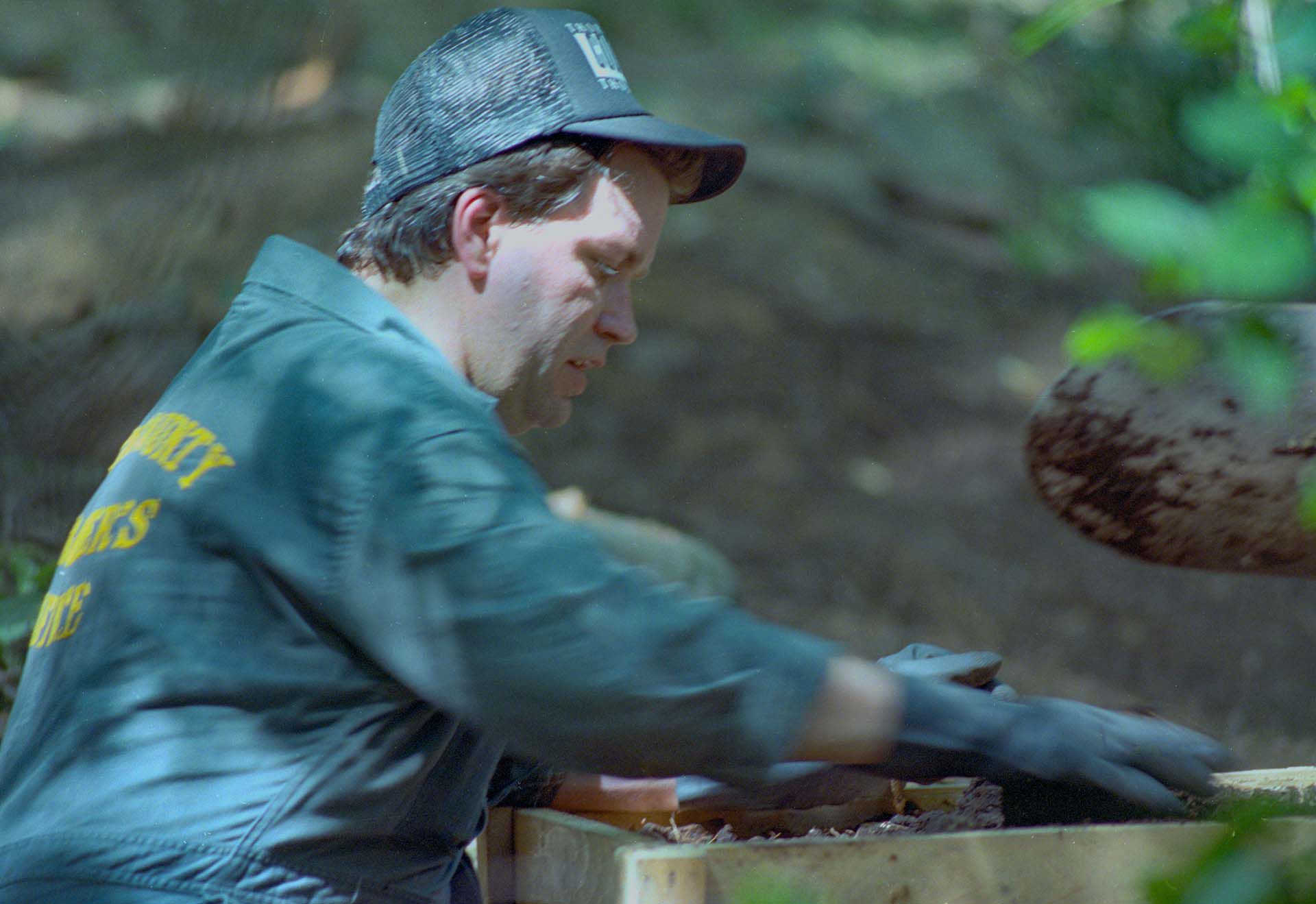 (Original Caption) Bath Township, Ohio: A member of the investigating team searching the yard of the former home of confessed mass murderer Jeffrey Dahmer, sifts through dirt looking for bone fragments (July 31st). The team discovered numerous human bone fragments (July 30th) believed to be the remains of Dahmer's first victim, Steven Hicks, back in 1978.