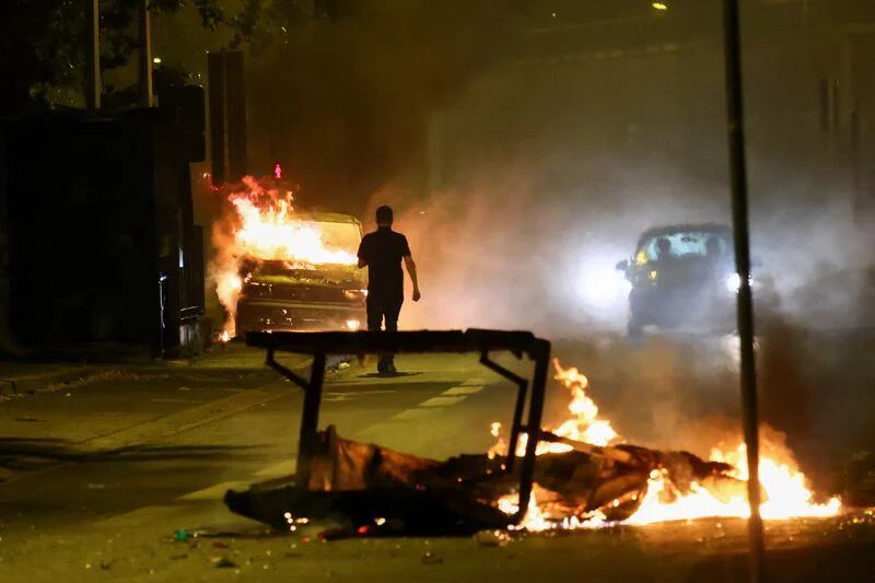 Una persona se encuentra cerca de un vehículo en llamas mientras continúan los disturbios tras la muerte (REUTERS/Yves Herman)