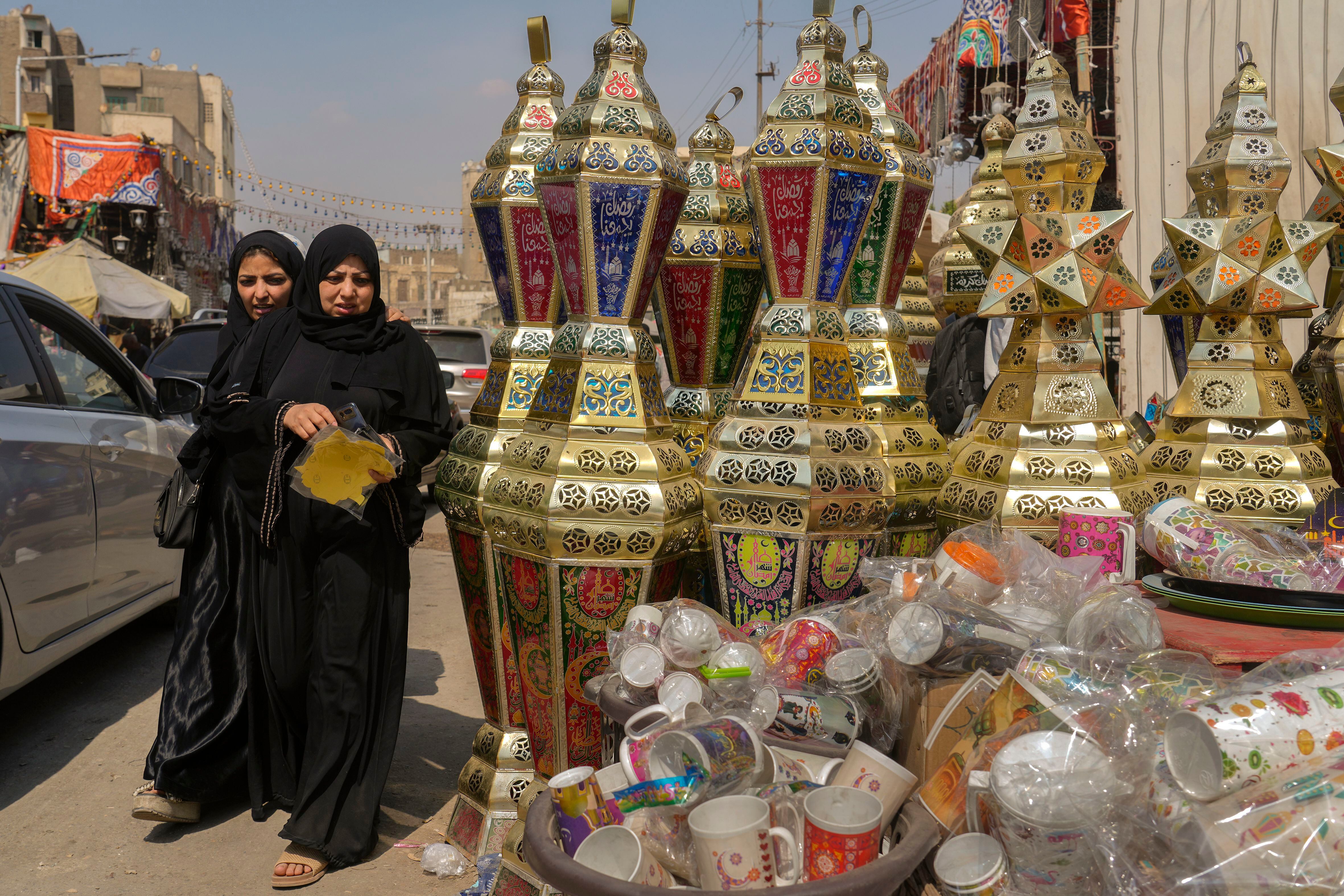 Unas mujeres compran lámparas tradicionales en el mercado de Sayyeda Zeinab previo al inicio del mes de ayuno del ramadán, en El Cairo, Egipto, el martes 21 de marzo de 2023. (AP Foto/Amr Nabil)