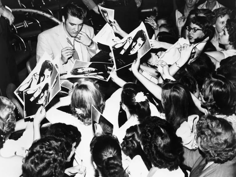 Elvis Presley firmando autógrafos a sus seguidores cuando su carrera estaba en la cima.
