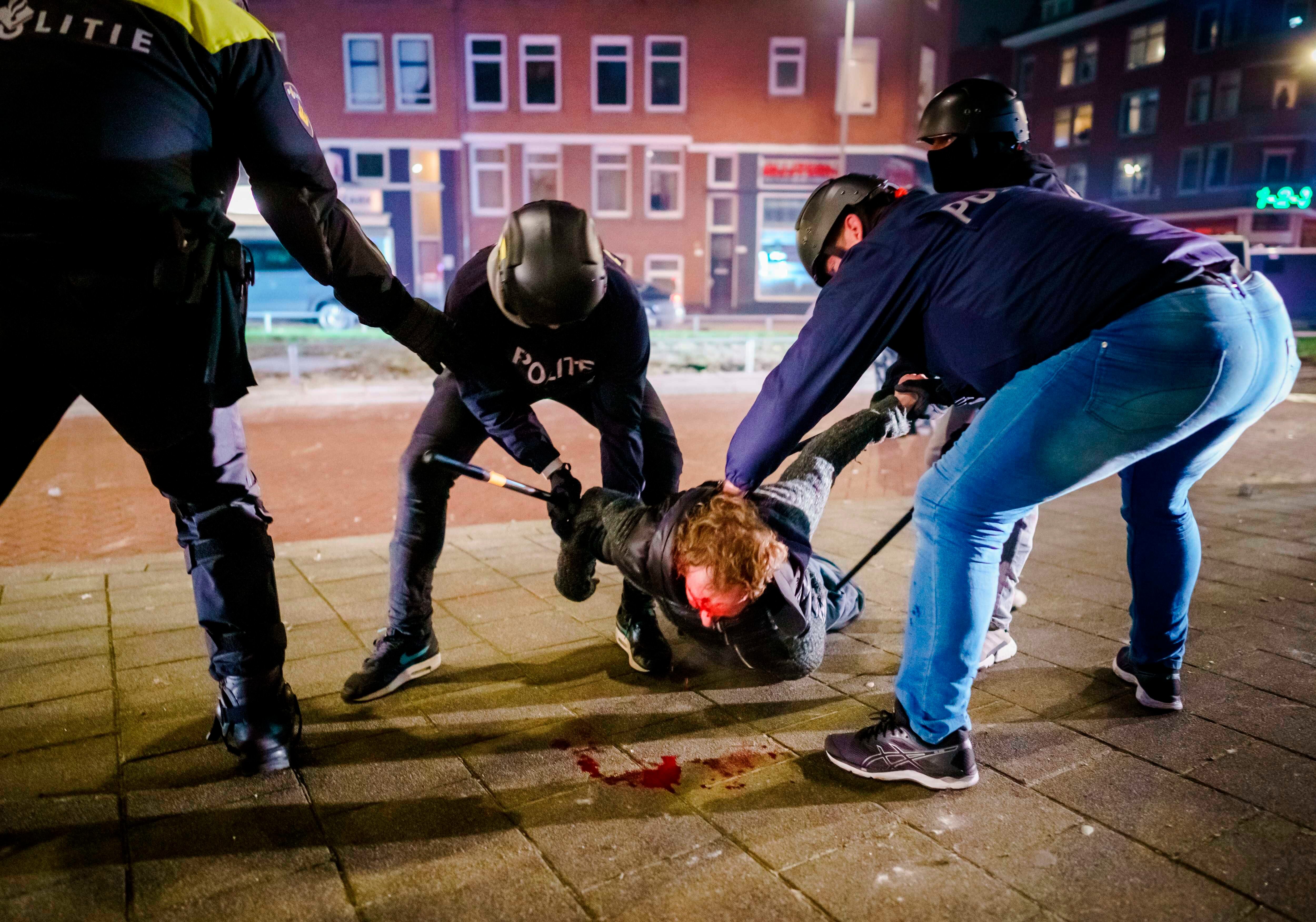 Un hombre es reducido por varios policías durante los distubios registrados anoche en Rotterdam, Países Bajos. EFE/EPA/MARCO DE SWART
