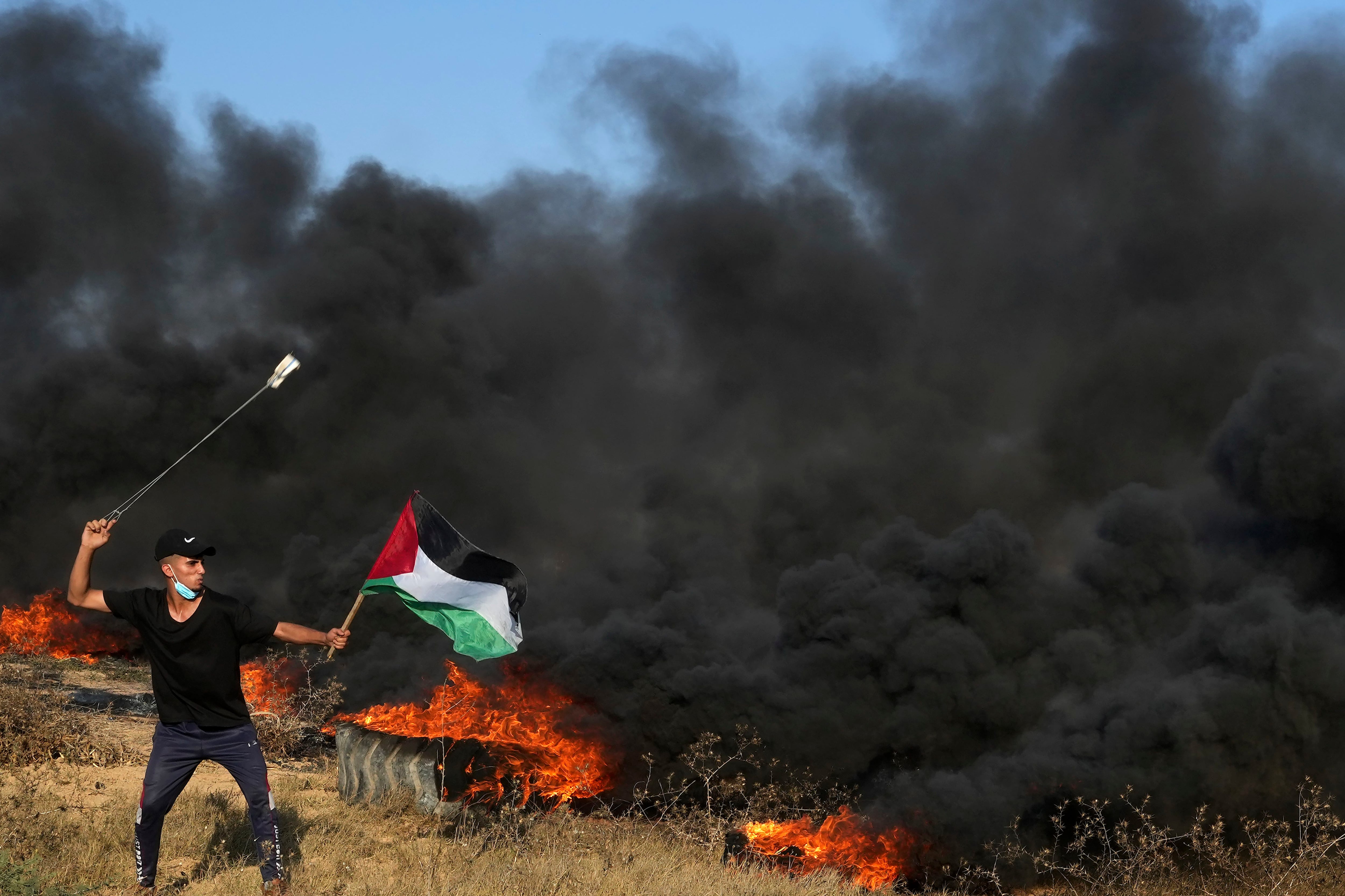 Un manifestante palestino arroja piedras con una honda durante choques con las fuerzas israelíes en la Franja de Gaza. Los palestinos fueron excluidos del acuerdo entre sauditas, israelíes y estadounidenses. (AP Foto/Adel Hana)