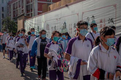 Los estudiantes con mascarillas esperan para entrar en una escuela para asistir al primer día de los exámenes anuales de ingreso a la universidad nacional de China en Pekín. EFE/EPA/ROMAN PILIPEY
